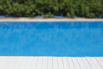 Wooden table mat with swimming pool and bushes in the background     