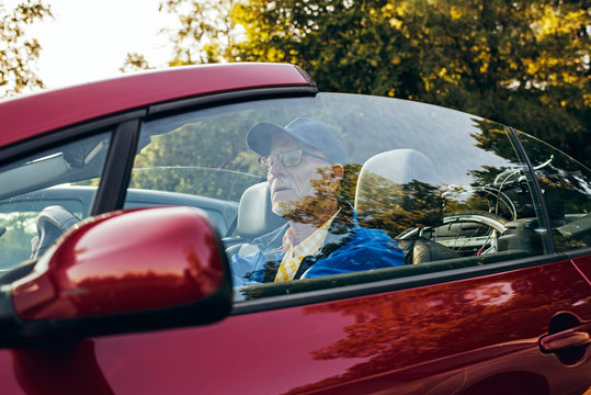 Senior Man Sitting In Sports Car Outdoors In Park.