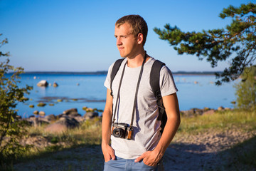 man with backpack and retro camera on the beach