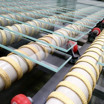 Szkło hartowane ESG. Elementy szklane ułożone na rolkach maszyny do hartowania szkla.