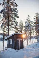 Small log cabin behind vaporing river in winter in Finland