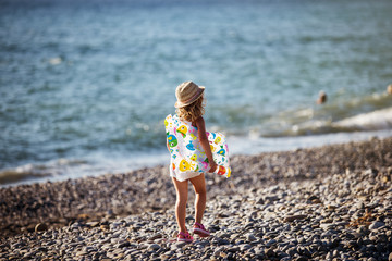Adorable little girl with inflatable air mattress on beach