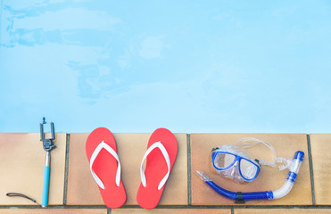 Hand hold, flip flop and mask near swimming pool