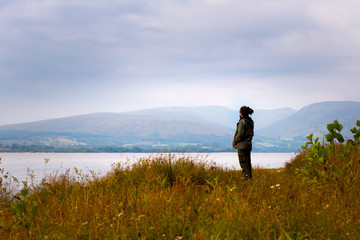 Hipster man standing by Loch Lomond, Scotland, UK