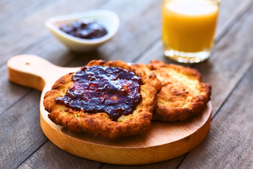 Freshly prepared traditional Hungarian deep fried flat bread called Langos made of a yeast dough, with jam spread on top  (Selective Focus, Focus on the front of the jam on the langos) ..
