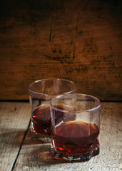 Two glasses of whiskey on dark old wooden background, selective