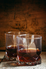Two glasses of whiskey on dark old wooden background, selective