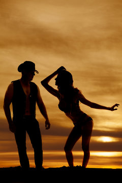 silhouette woman in bikini lean to side hand out to cowboy