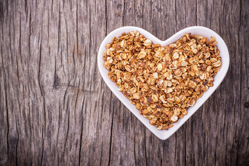 Home caramel granola in a white ceramic dish shape of heart