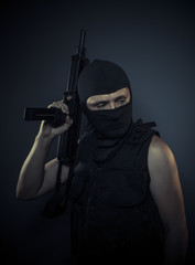 Fototapeta na wymiar Thug, terrorist carrying a machine gun and balaclava