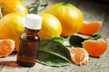 Aromatic tangerine oil, with tangerines on a wooden background,