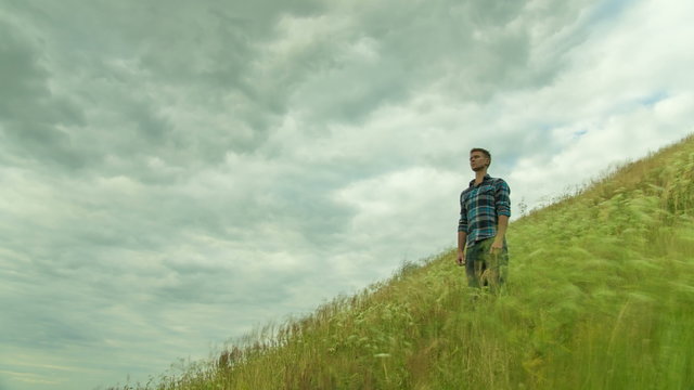 The man stand on the hill with green grass by thunderstorm sky background