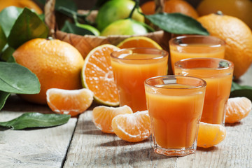 Fresh tangerine juice with slices of mandarin on old wooden back