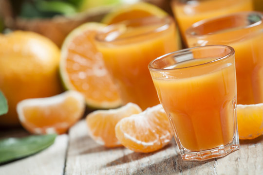Fresh tangerine juice with slices of mandarin on old wooden back