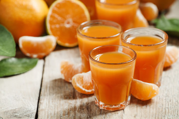 Fresh tangerine juice with slices of mandarin on old wooden back