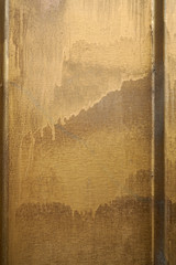 Small part of metal door sprinkled with golden brown paint