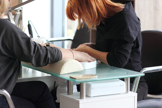 Woman in nail salon receiving manicure by beautician. Woman getting manicure at beauty salon 