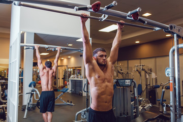 Very power athletic guy bodybuilder , execute exercise with horizontal bar