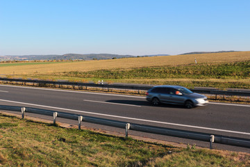 Car driving on highway in sunny weather, motion blur.