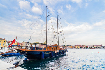 A galleass anchored among ships in the Adriatic sea with a view of the old city core buildings on the coast