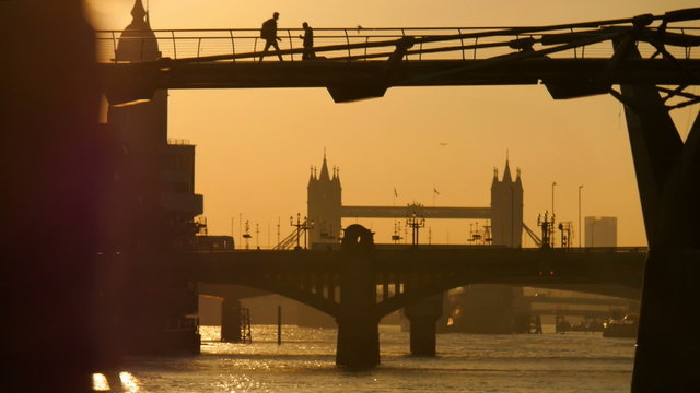 Early Morning Sunrise Over Millennium Bridge And Tower Bridge As People Commute To Work.