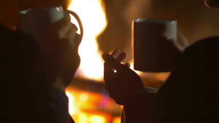 The pair sit and drink tea (coffee), talk, kiss and laughter in the camping tent by sky and bonfire background. Real time capture. Shot with crane and Red Cinema camera - Powered by Adobe