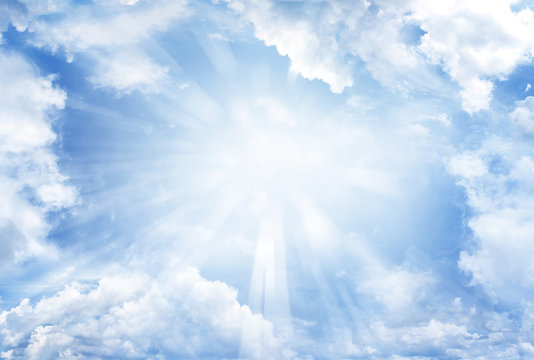 Rays of light shining in blue sky clouds