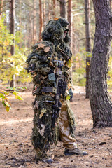 Sniper in forest/Sniper in camouflage stands with rifle in forest