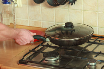 Closeup of human hand with frying fry pan.