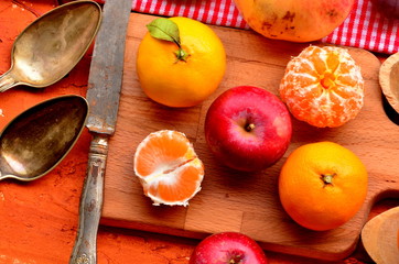 Figs, persimmon, pomegranate, avocado, apples and mandarines (tangerines) on rough background