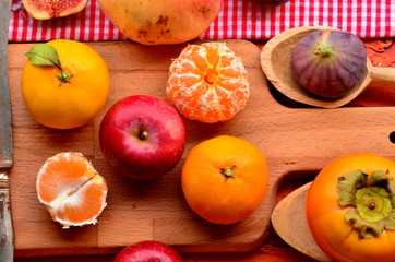 Naklejka na ściany i meble Figs, persimmon, pomegranate, apples and mandarines (tangerines) on rough background