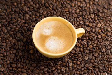 Yellow coffee Cup and roasted coffee beans around