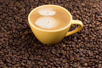 Yellow coffee Cup and roasted coffee beans around