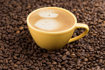 Yellow coffee Cup and roasted coffee beans around