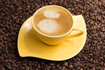 Yellow coffee Cup and roasted coffee beans around