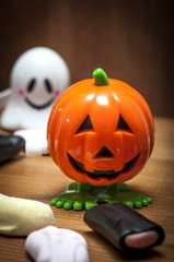 A creepy Halloween pumpkin and a ghost on a wooden table surrounded by licorice and other candy