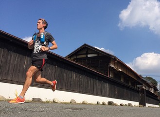 Man running on beautiful blue aky morning past traditional Japanese house