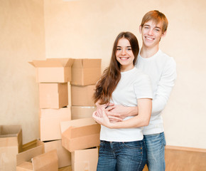 Fototapeta na wymiar happy young family hugging on a background of cardboard boxes