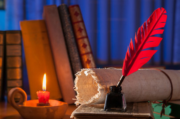 Red quill pen, black inkwell and a rolled papyrus sheet on an old book with a blue background