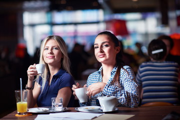 girls have cup of coffee in restaurant