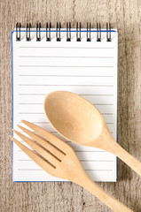 Open cookbook and kitchenware on wooden background