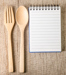 Open cookbook and kitchenware on wooden background