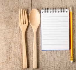 Open cookbook,pencil and kitchenware on wooden background