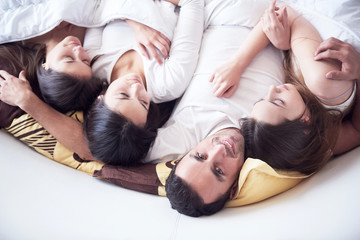 handsome man in bed with three beautiful woman