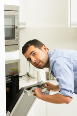 Hispanic male wearing blue shirt in modern kitchen leaning