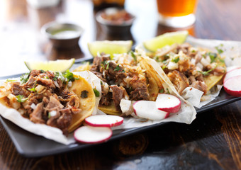 plate of authentic mexican street style tacos with radish slices