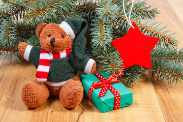 Teddy bear with gift for Christmas, spruce branches and red star