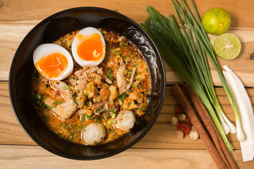 bowl of noodles with vegetables and soft boiled egg on wooden ta