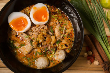 bowl of noodles with vegetables and soft boiled egg on wooden ta