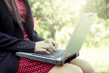 Fototapeta premium Woman using laptop in park on sunny day